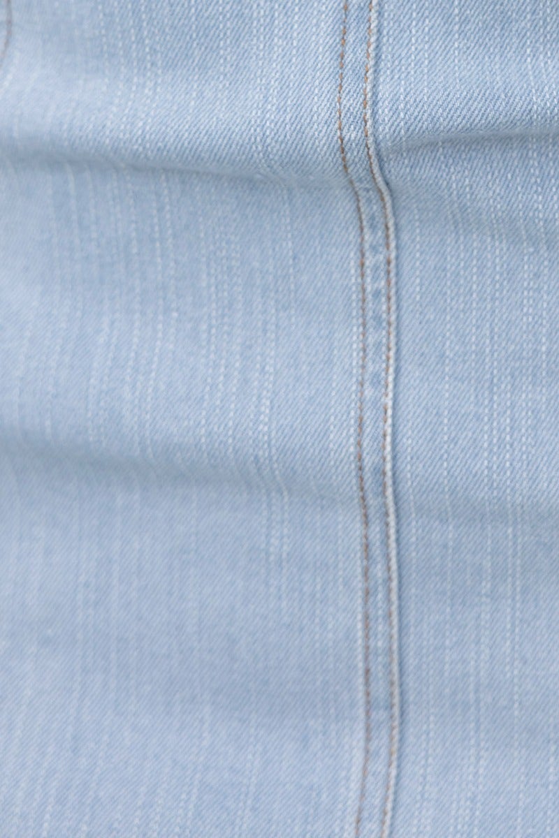 Close-up of light blue denim fabric, showcasing texture and stitching details, ideal for denim midi dresses.