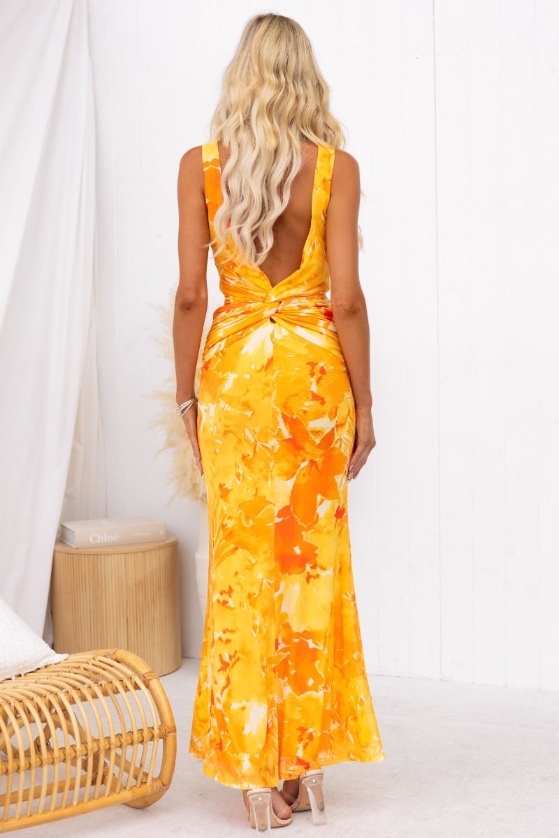 Back view of Rene Maxi Dress in yellow floral design, showcasing its twist detail and elegant silhouette.