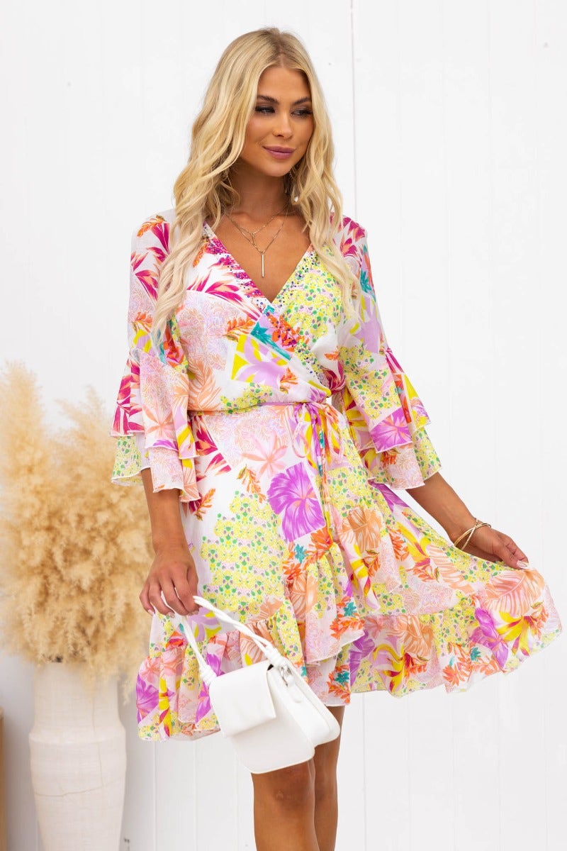 Model wearing a colorful floral Fools Gold Wrap Dress with V-neckline and flared sleeves.
