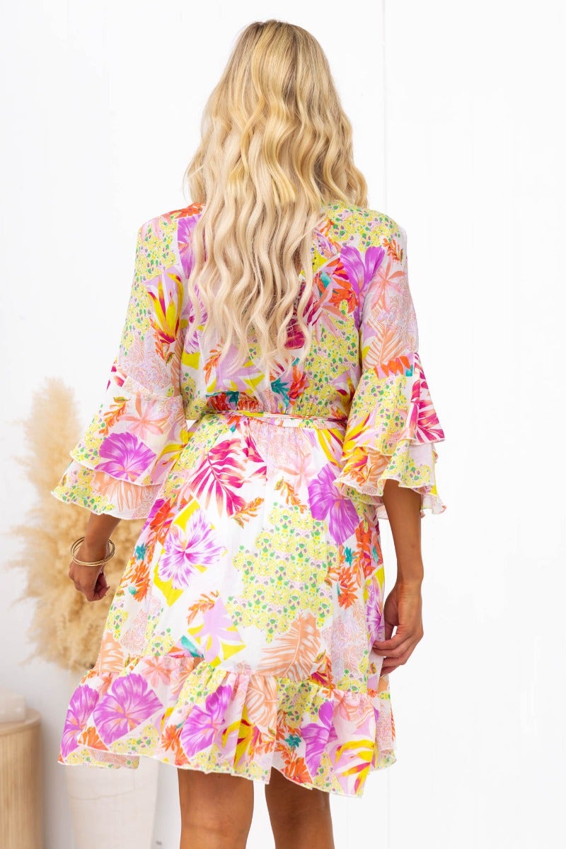 Model wearing a Fools Gold Wrap Dress featuring vibrant floral patterns and flared sleeves from the back.