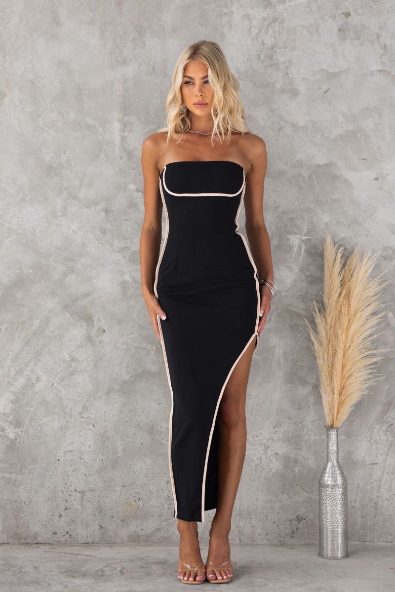 Stazi Maxi Dress: Black bodycon strapless dress with asymmetric hem and side slit, styled elegantly against a neutral background.