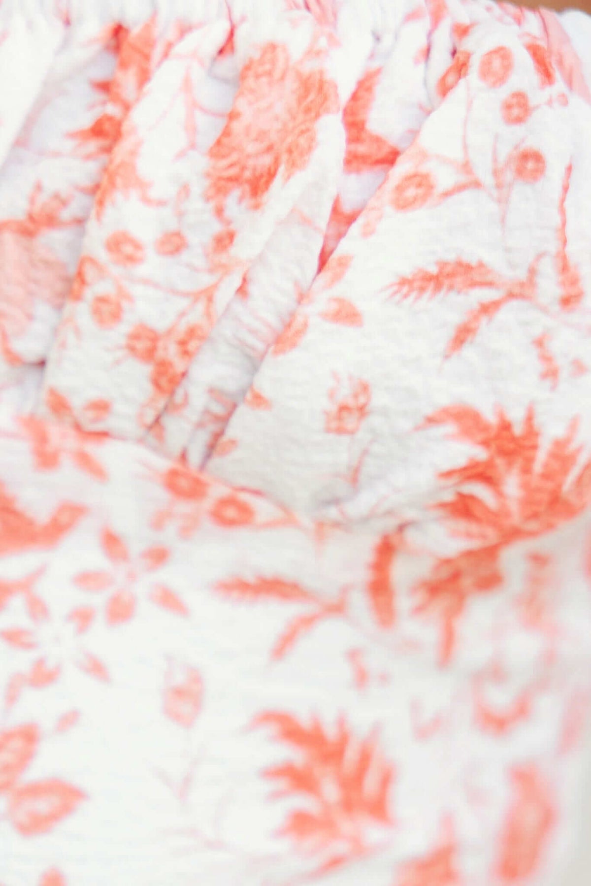 Close-up of floral print fabric in orange and white, featuring a textured design for the Peyton Dress.