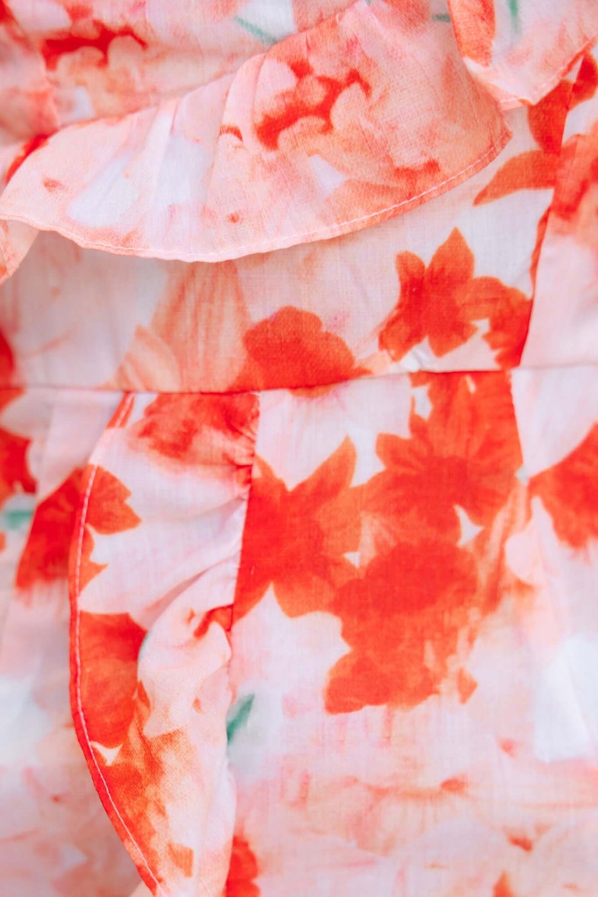 Close-up of floral print fabric featuring ruffle trim in vibrant orange and pink tones for the Night Changes Dress.