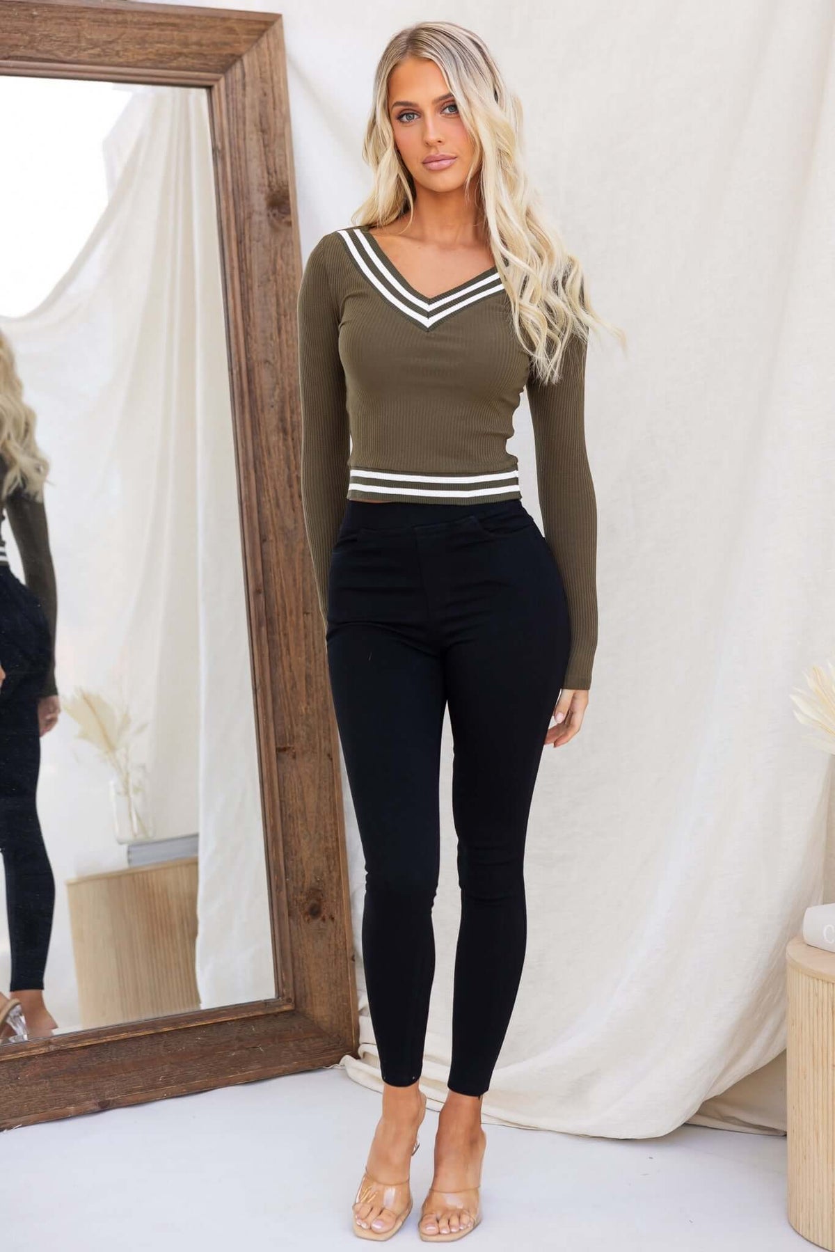 Model wearing Ivan Pants jeggings, mid-high waist black pants with elastic waistband and pockets, styled with a green top.