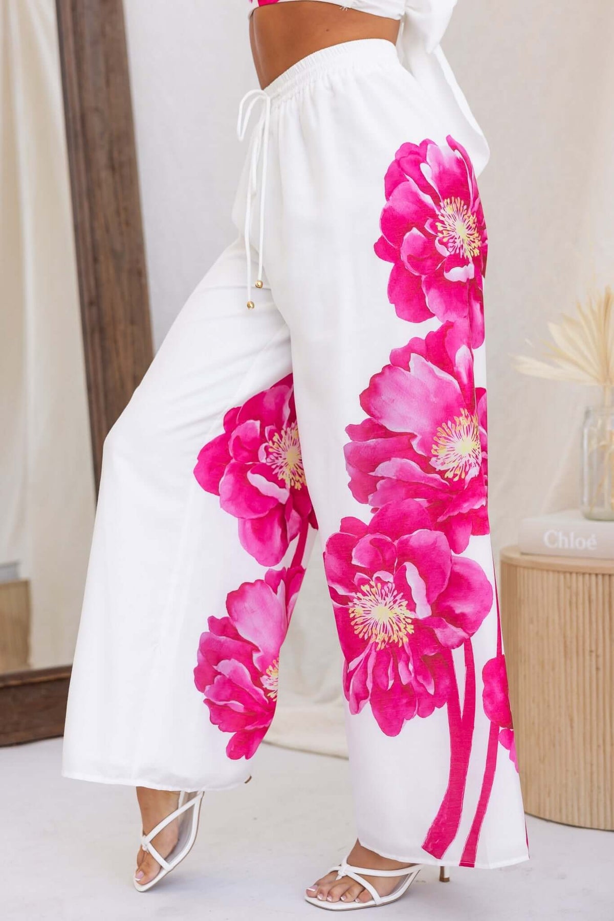 Faly Pants featuring a mid-high waist, elastic waistband, and vibrant pink floral design on a lightweight fabric.