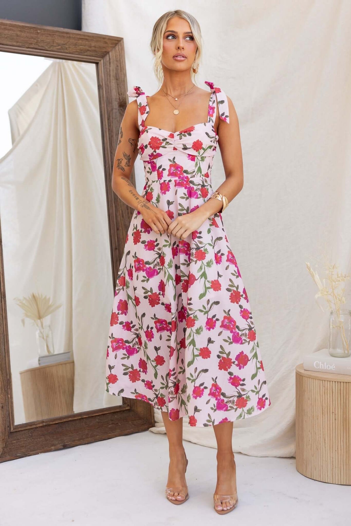 Floral print midi dress with adjustable tie straps, styled in a bright and elegant setting.
