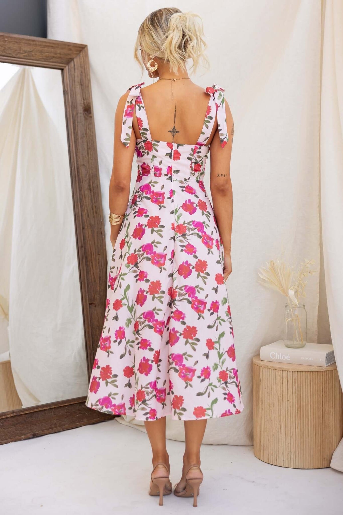 Back view of floral print midi dress with adjustable tie straps, showcasing its elegant design and fit.