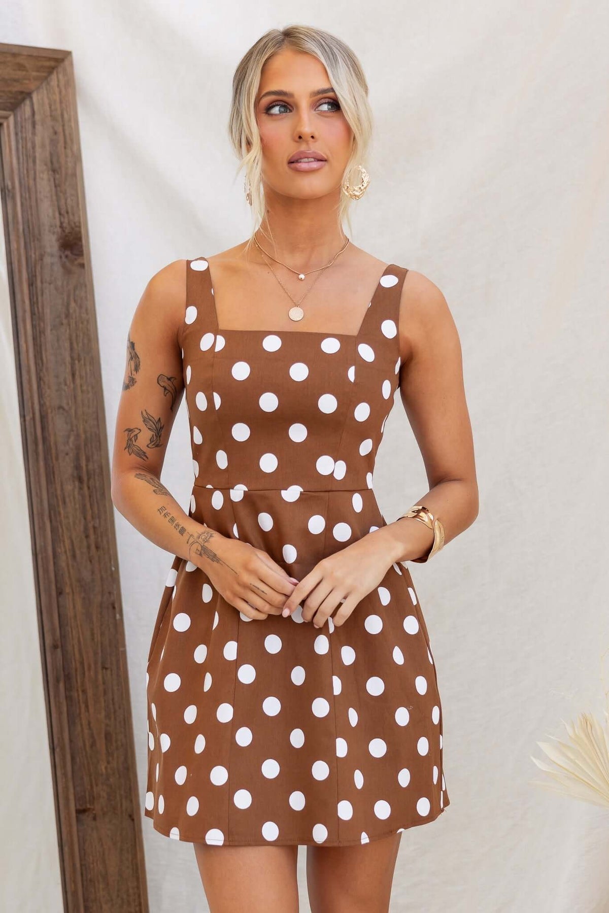 Isibel Dress in brown with white polka dots, featuring adjustable straps and a fitted silhouette.