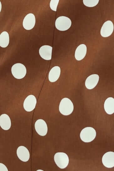 Close-up of brown fabric with white polka dots, showcasing texture and pattern for the Isibel Dress.