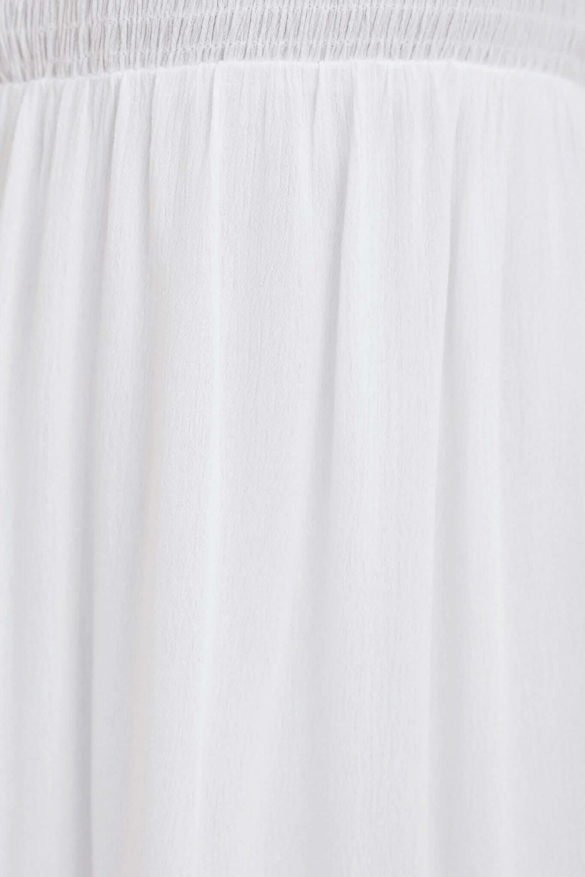 Close-up of the soft, white fabric showcasing the lightweight texture and elastic waistband of the Lisle Dress.