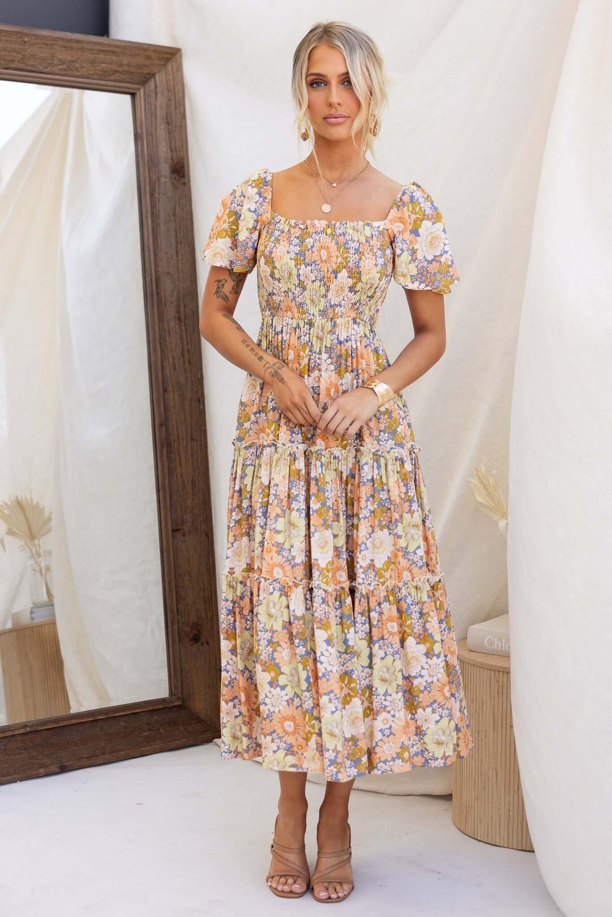 Nostalgic maxi dress with floral print, elastic bodice, and pockets, styled against a neutral backdrop.