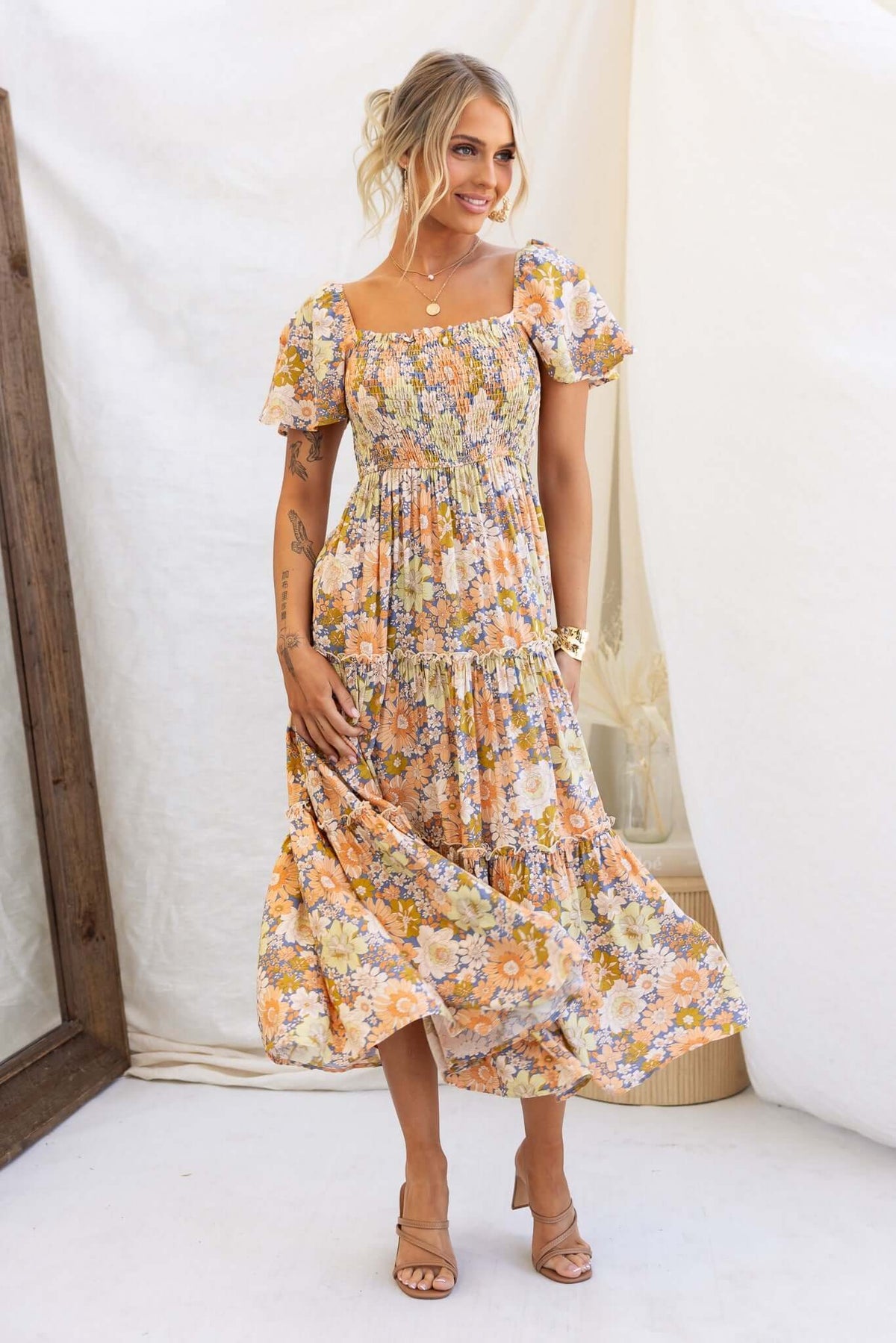 Nostalgic maxi dress with floral pattern, elastic bodice, and pockets, worn by a model in a bright, airy setting.