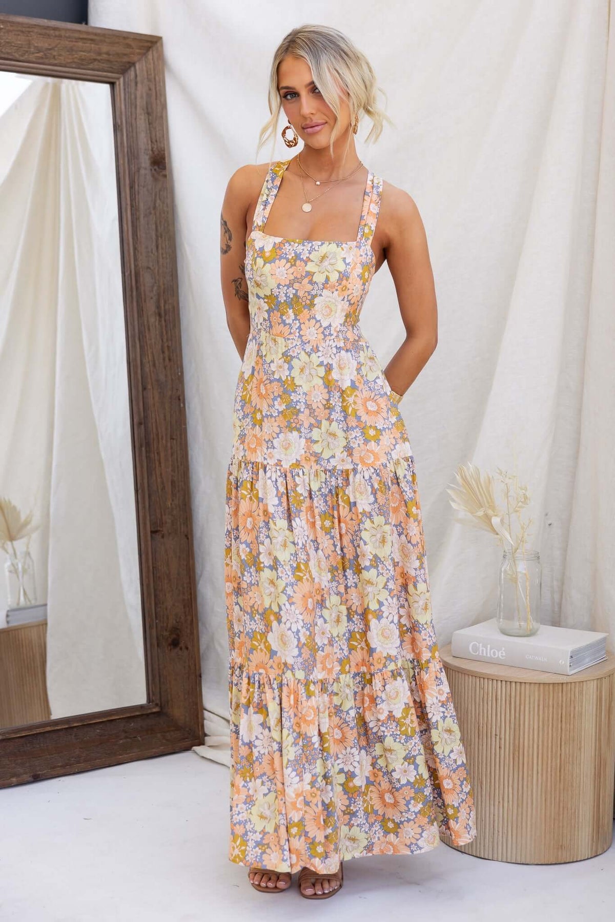 Etsie Maxi Dress displayed on model, featuring a floral pattern, halter neckline, and layered skirt in a stylish setting.