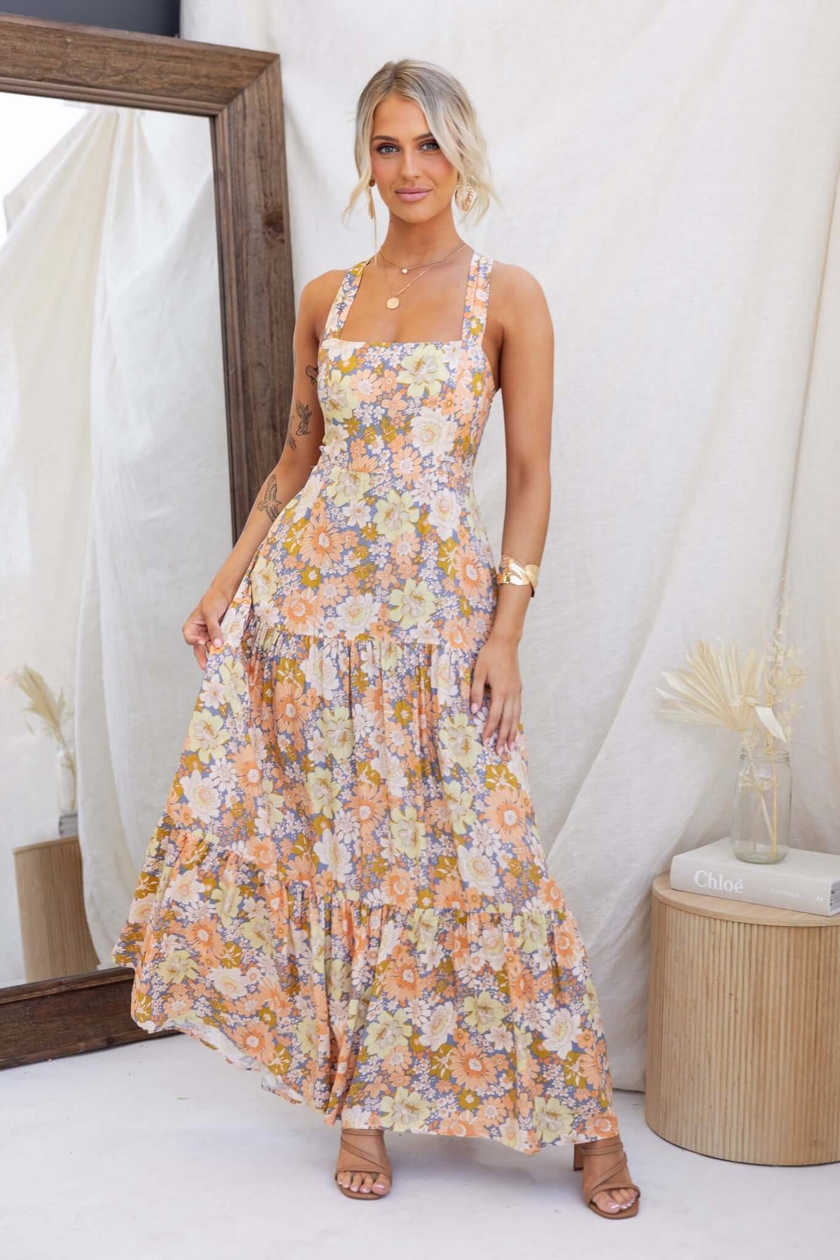 Model wearing Etsie Maxi Dress with floral print, adjustable halter neckline, and pockets in a stylish setting.