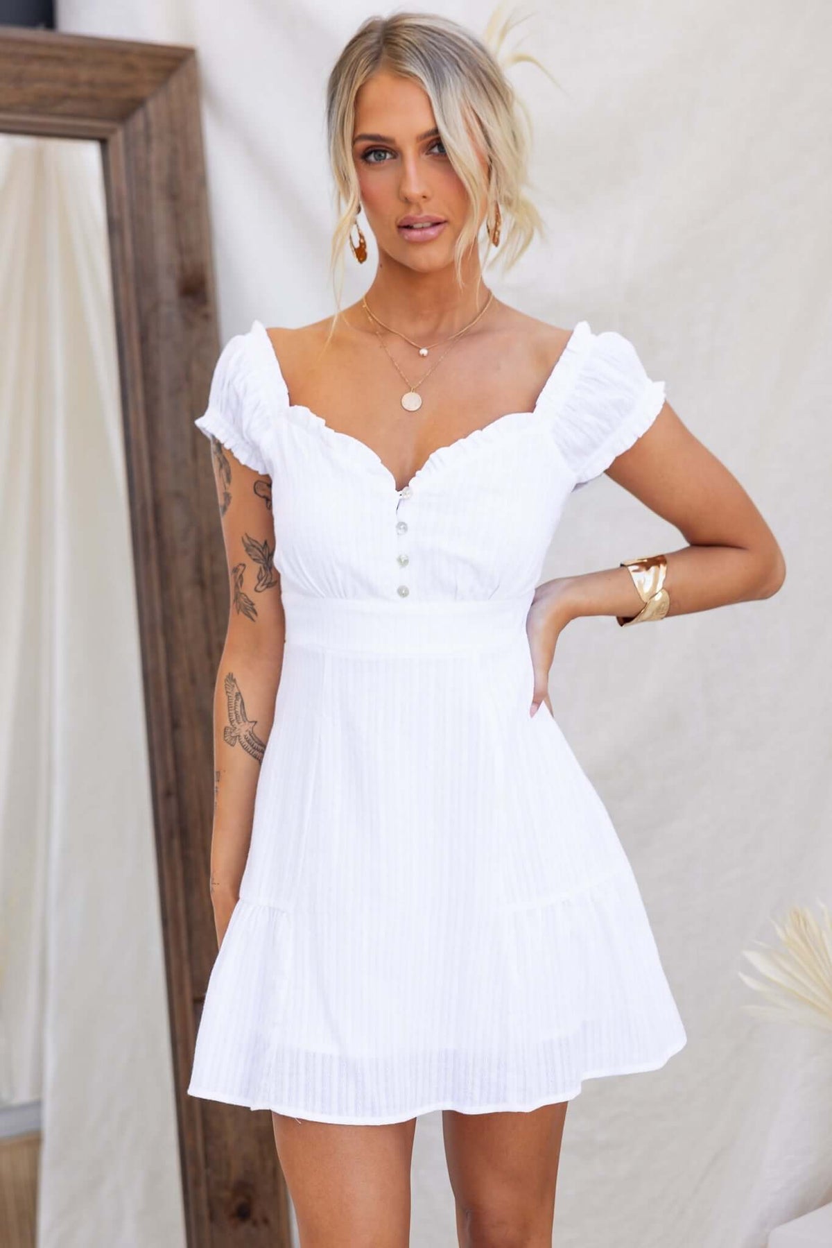 Model wearing a Calyssa Dress with elastic sleeves, button-up bust, and white cotton fabric.