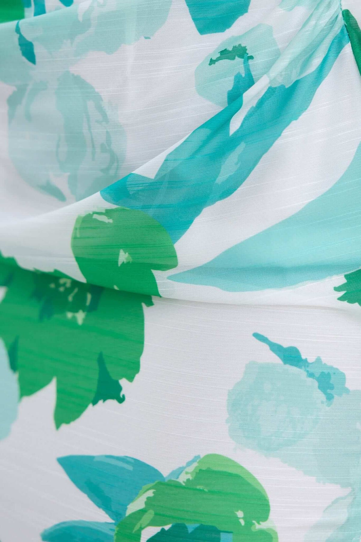 Close-up of the Riverside Maxi Dress featuring a floral pattern in shades of green and blue on lightweight fabric.