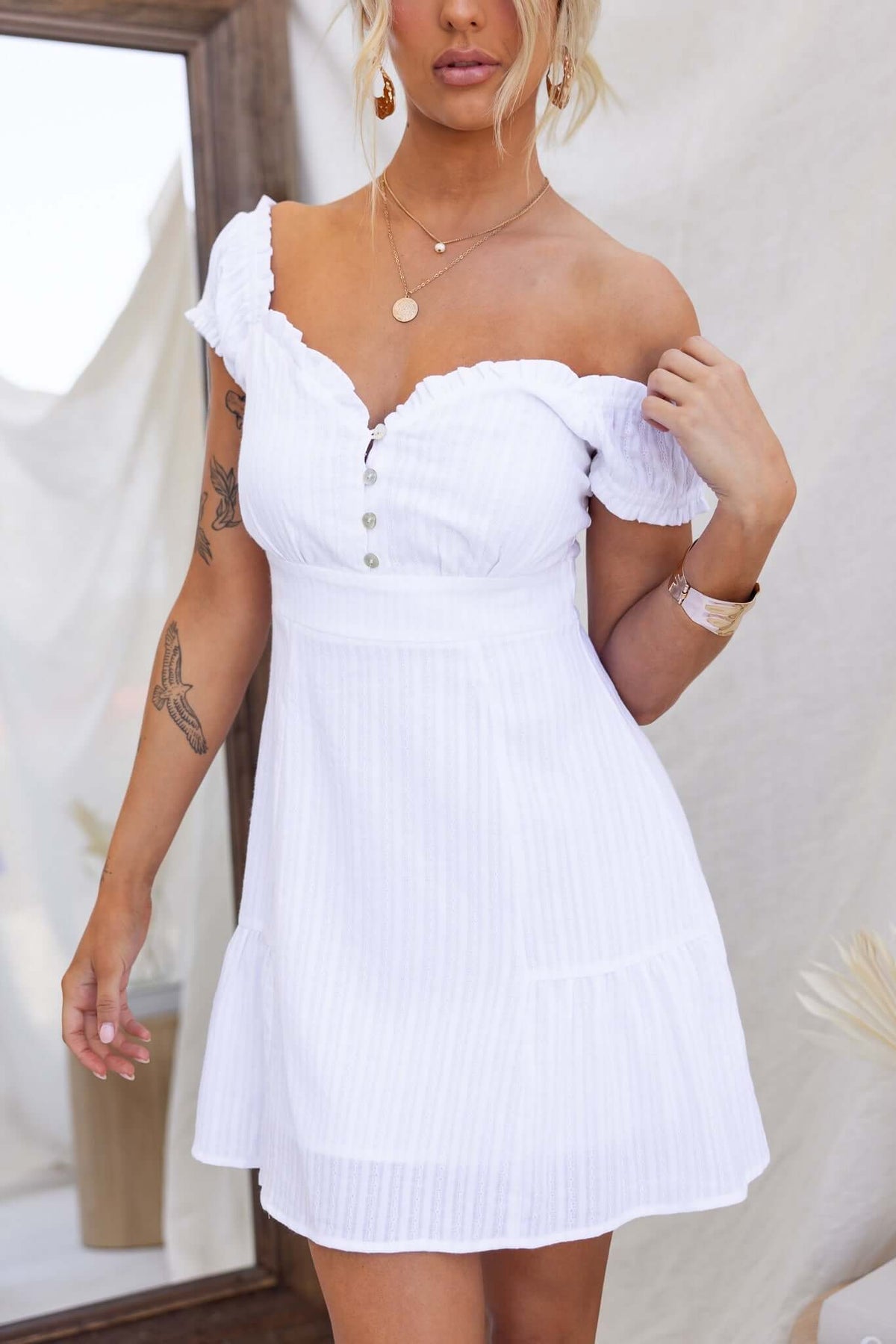 Calyssa Dress in white with elastic sleeves, button-up bust, and lined cotton fabric, worn by a model.