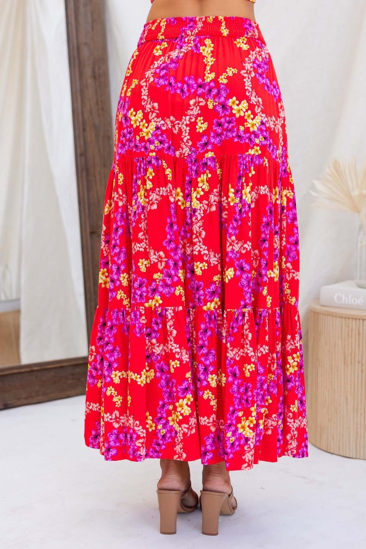 Hadid Maxi Skirt in vibrant red with floral print, featuring a mid-high waist, pockets, and a flowing design.