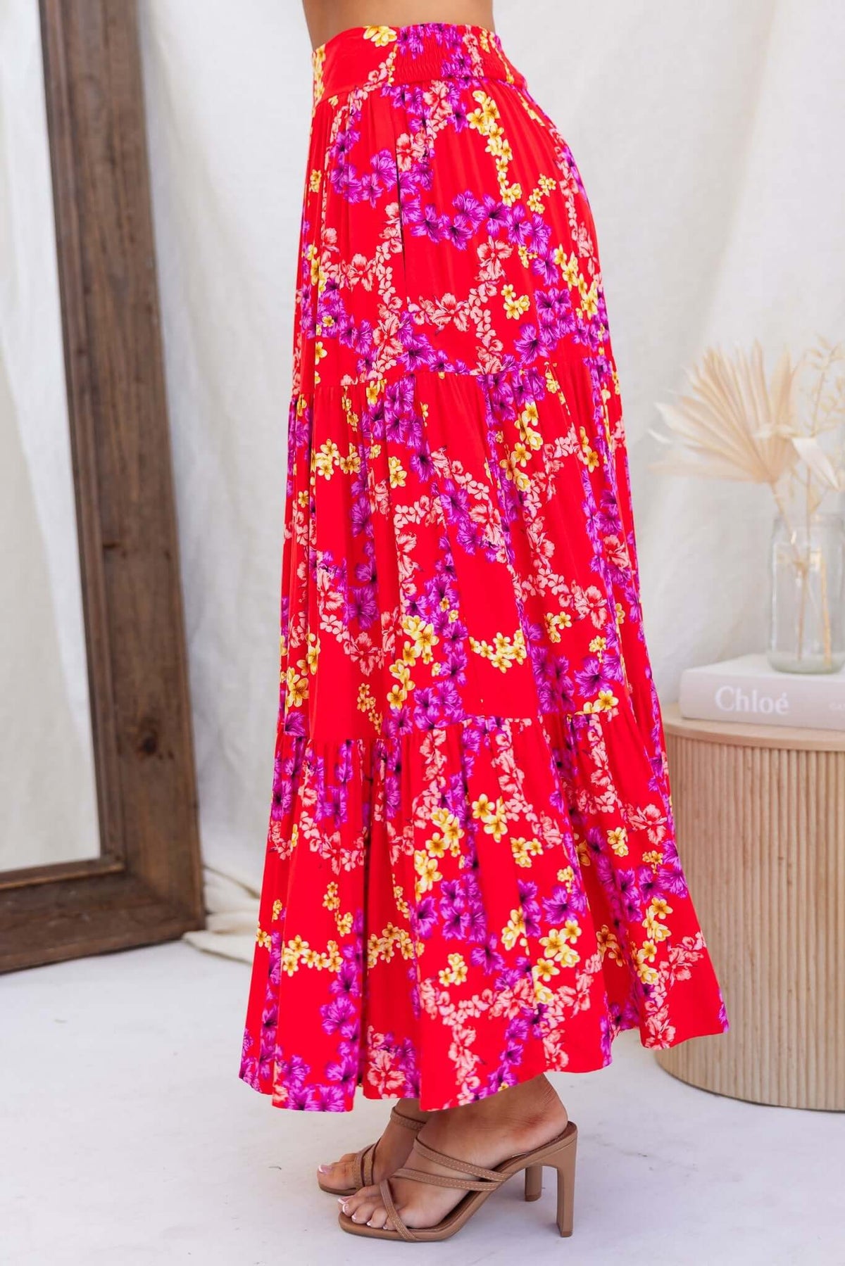 Hadid Maxi Skirt in vibrant red with floral print, featuring a mid-high waist and pockets, styled with sandals.
