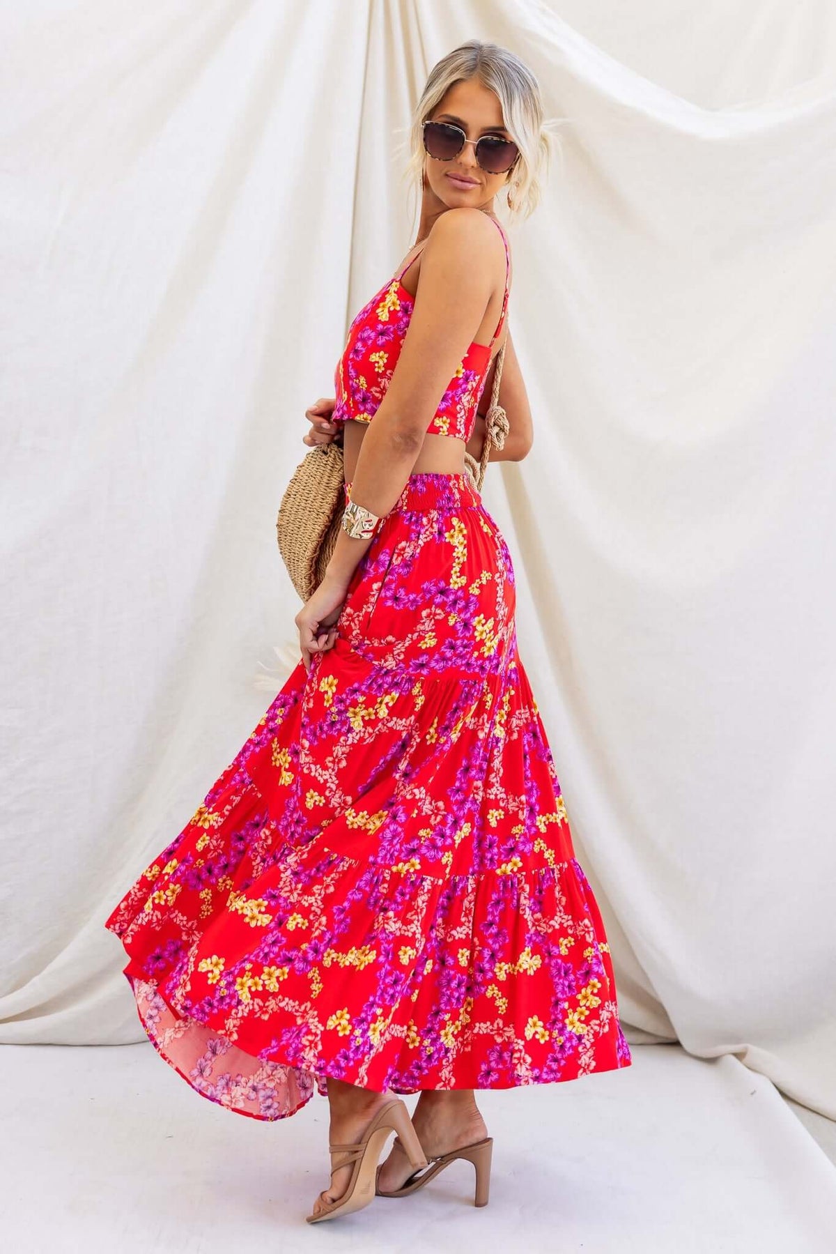 Model wearing a vibrant red floral Hadid Maxi Skirt with a matching top, showcasing a stylish and feminine summer outfit.