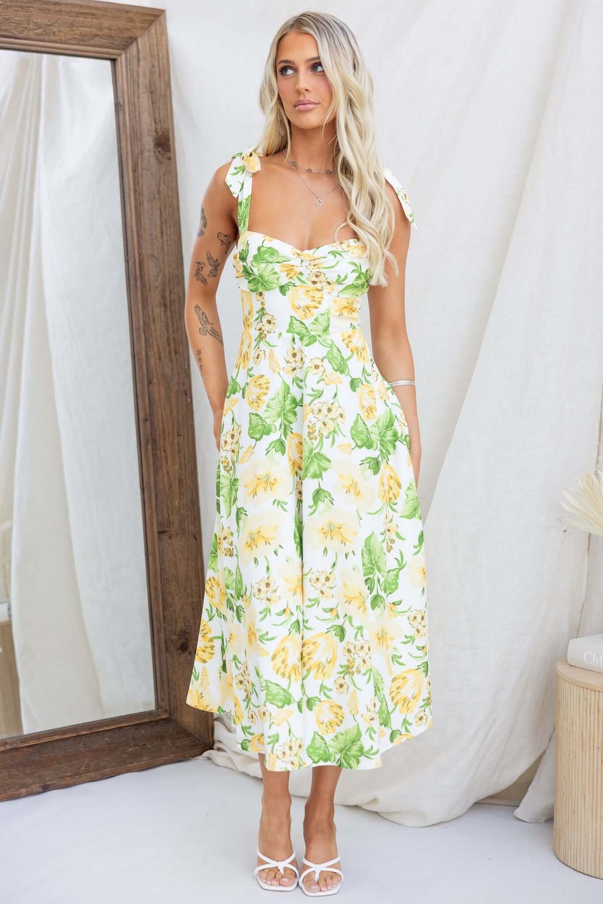 Floral print midi dress with adjustable tie straps and invisible zip, styled by a model in front of a mirror.
