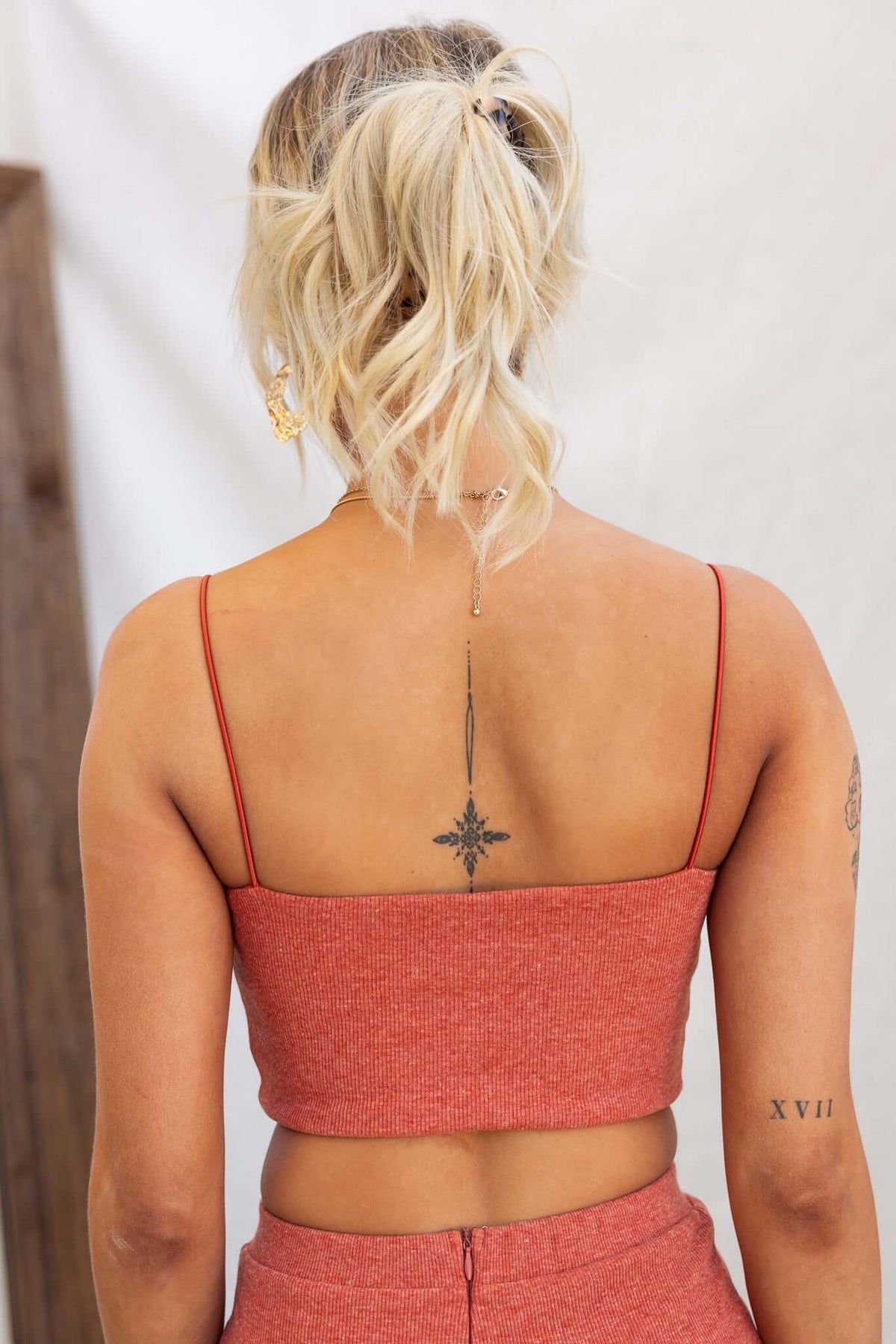 Back view of a woman wearing a ribbed red orzo top with spaghetti straps, showcasing a tattoo.