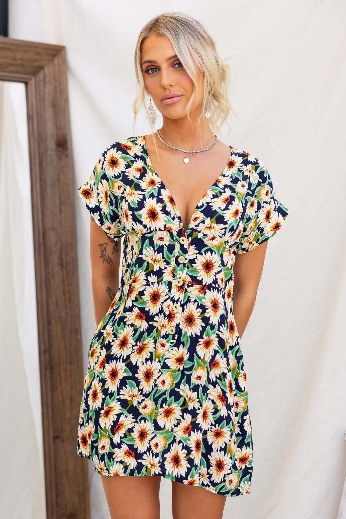 Navy floral dress with V-neckline and button-up front, featuring pockets and short sleeves.