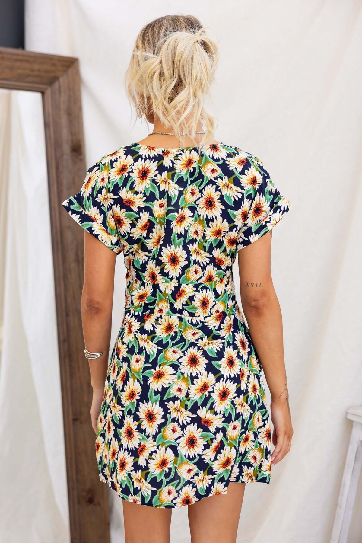 Back view of a navy dress featuring a colorful sunflower print, short sleeves, and a relaxed fit.
