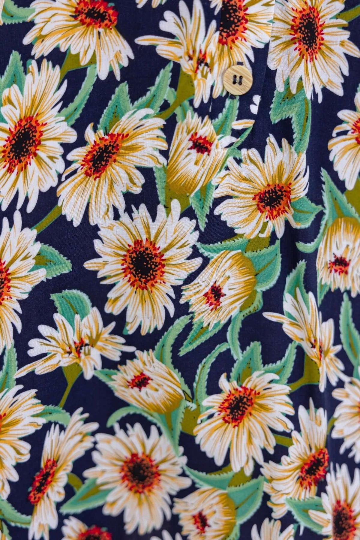 Navy dress with sunflower print featuring a button-up front and pockets, perfect for summer wear.