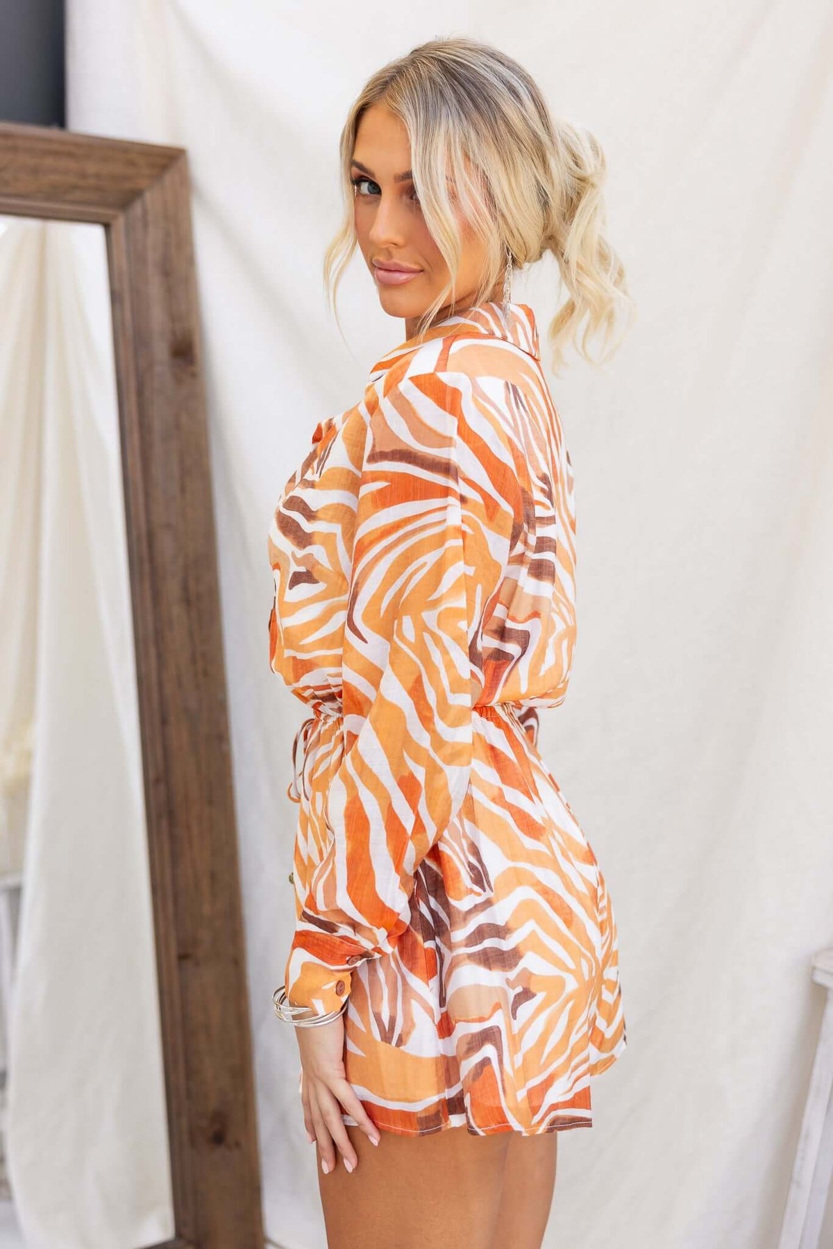 Model wearing the Oregon Playsuit, featuring an orange and white zebra print design and a cinched waist.