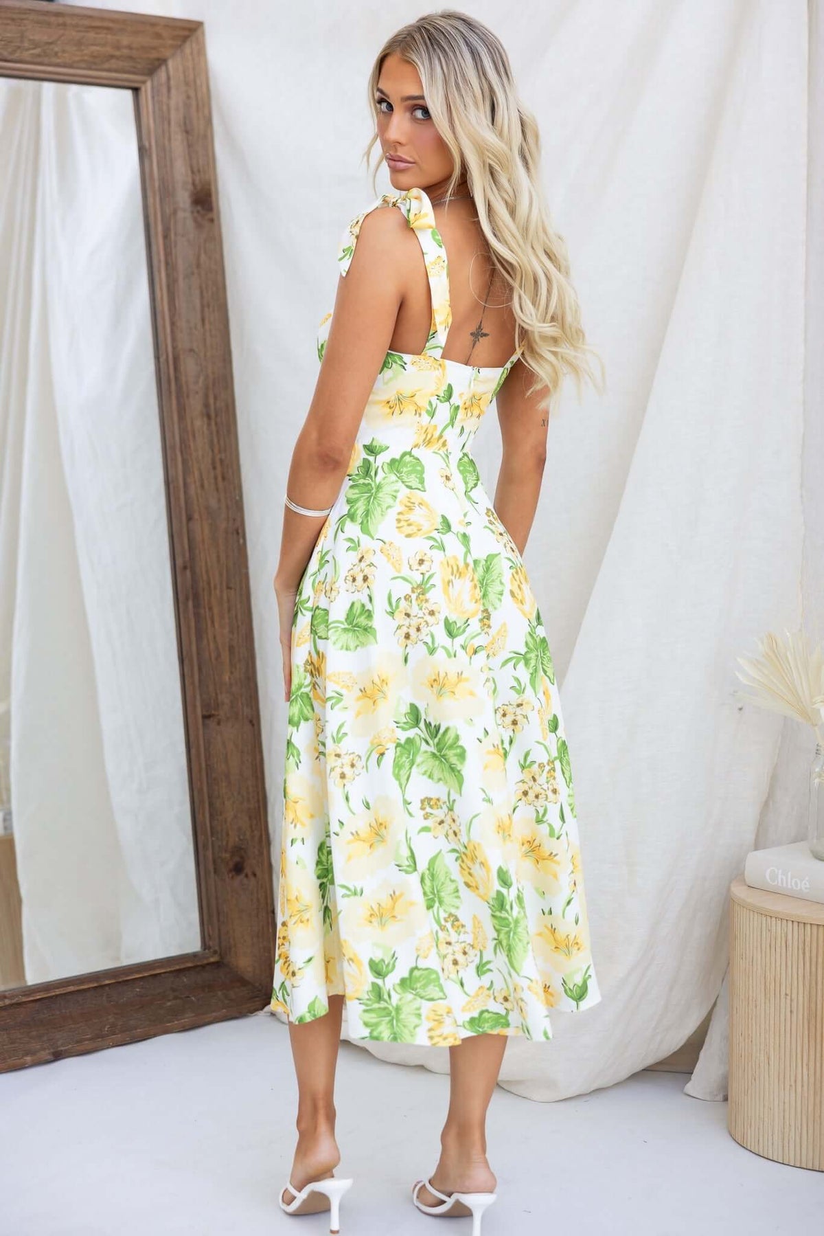 Back view of a floral print midi dress with adjustable tie straps and a fitted bust, perfect for summer outings.
