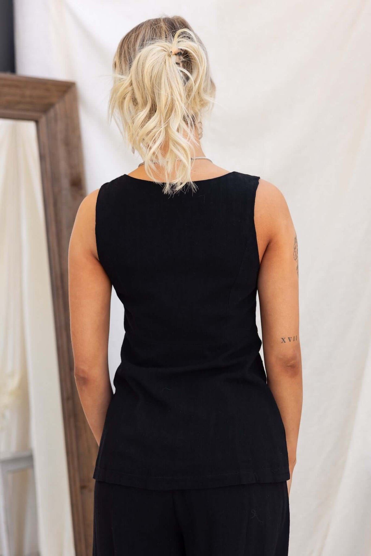 Back view of a woman wearing a black vest style top, showcasing the clean lines and linen look.