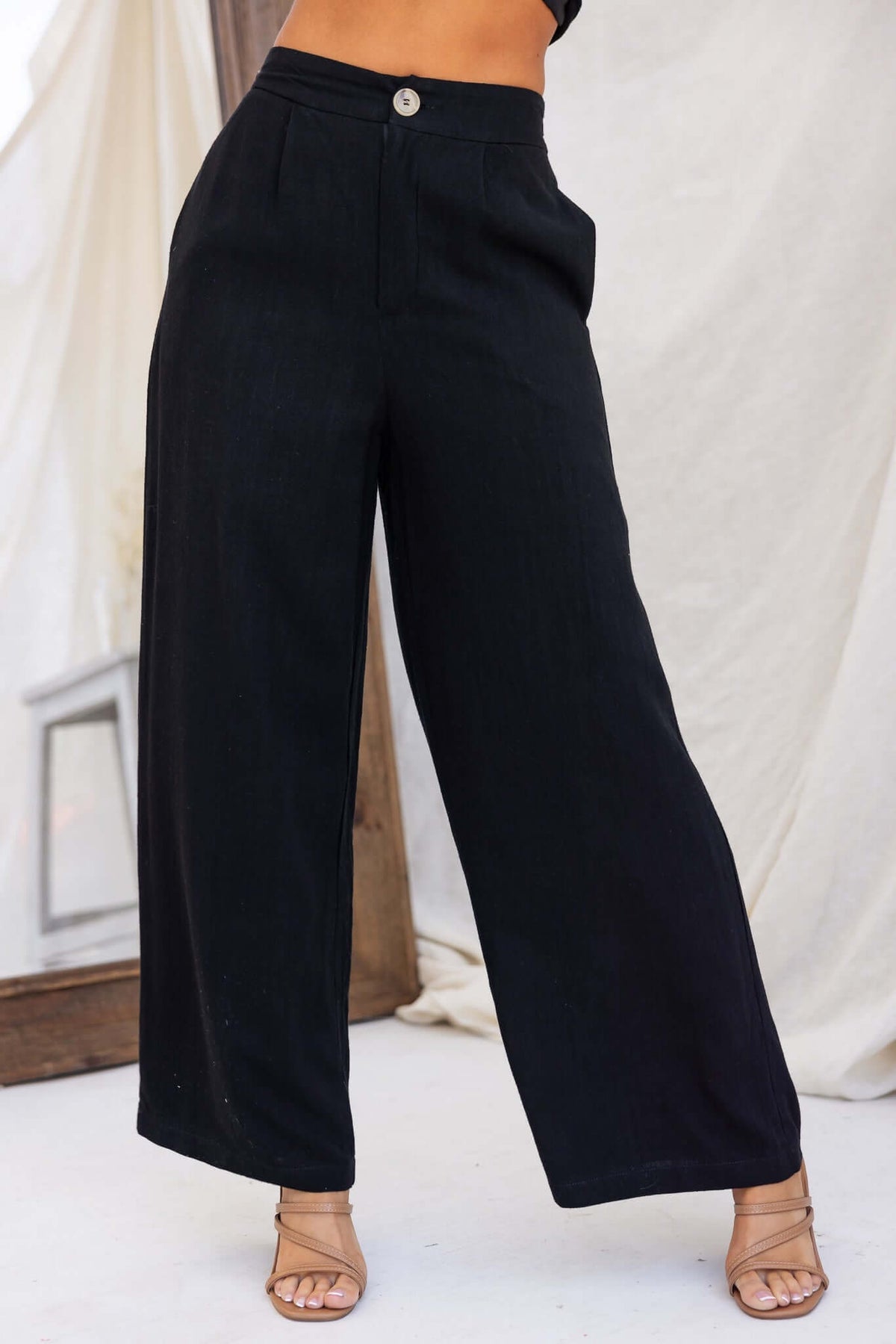 Model wearing Bexley black pants with a mid-high waist and pockets, showcasing a linen look and relaxed fit.