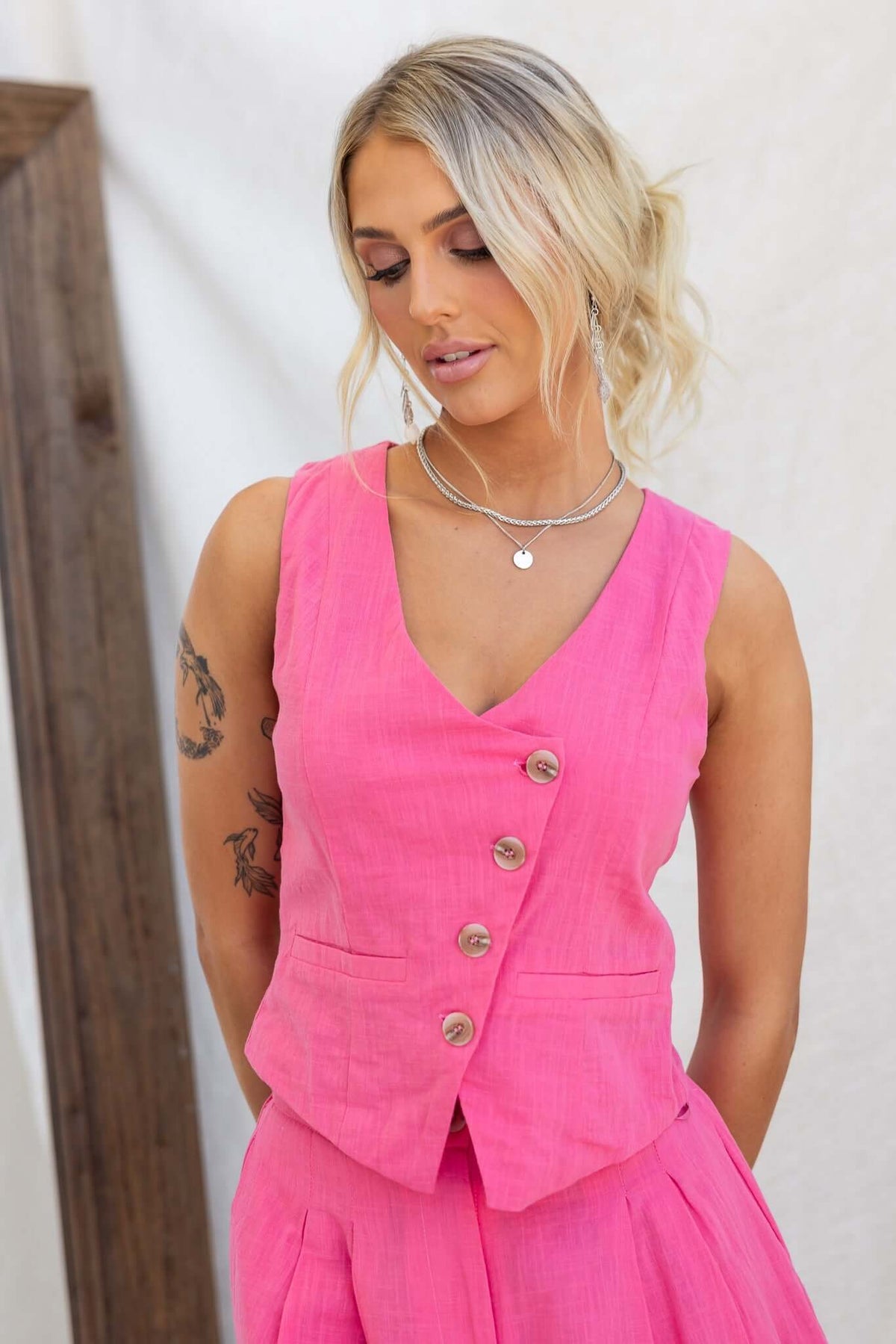 Model wearing a pink Qaycee Top vest with button-up front and faux pockets, showcasing a stylish summer look.