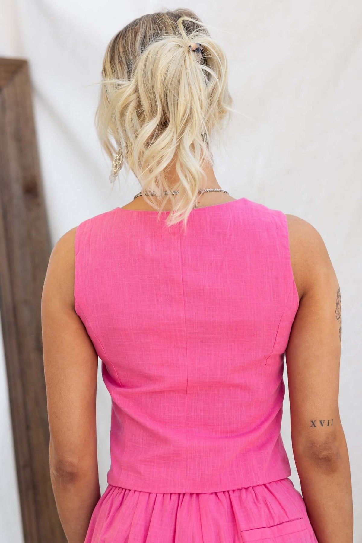 Back view of a woman wearing a pink Qaycee Top, showcasing its vest style and smooth fabric.