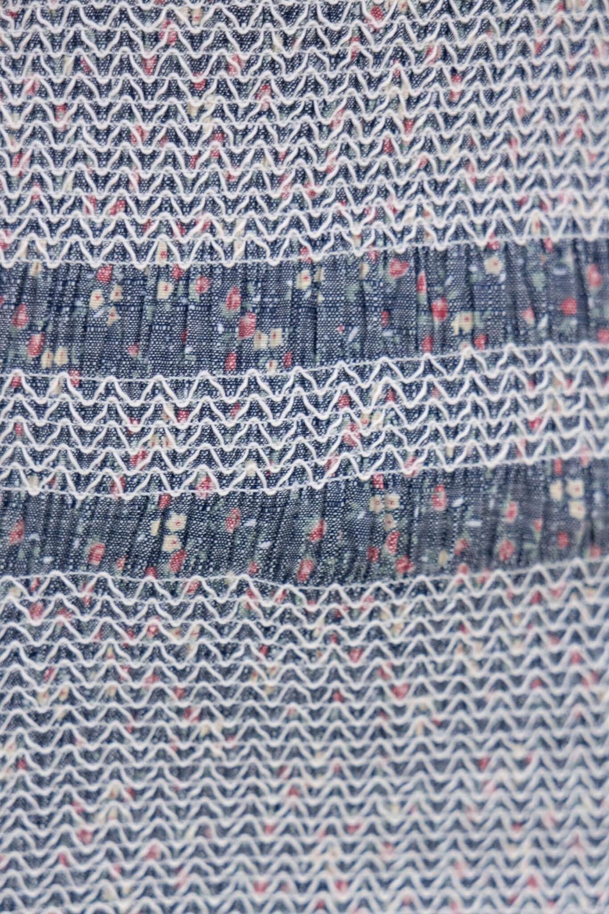 Close-up of textured fabric with floral patterns and elastic detailing suitable for dresses, resembling linen.