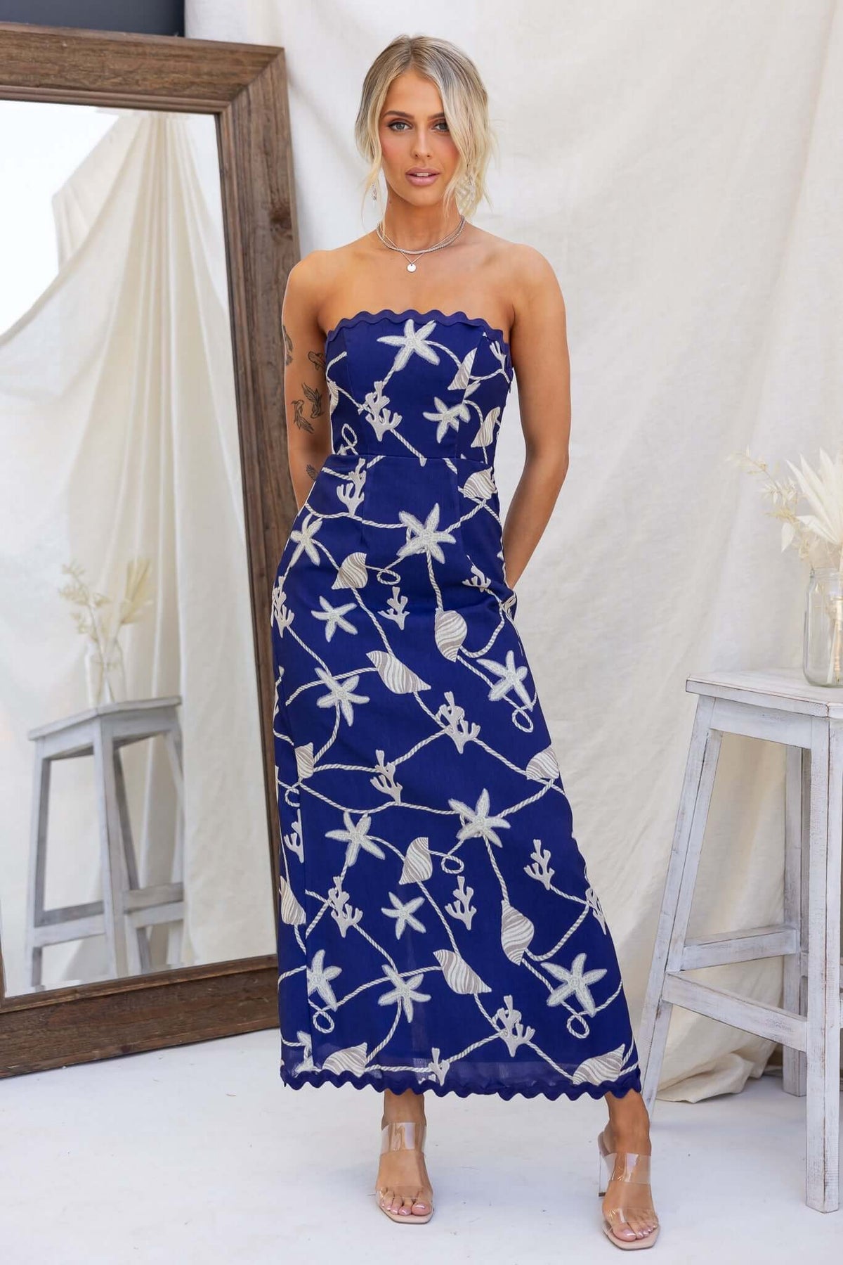 Model wearing a navy strapless Safran maxi dress with floral design, featuring a back split and lined interior.
