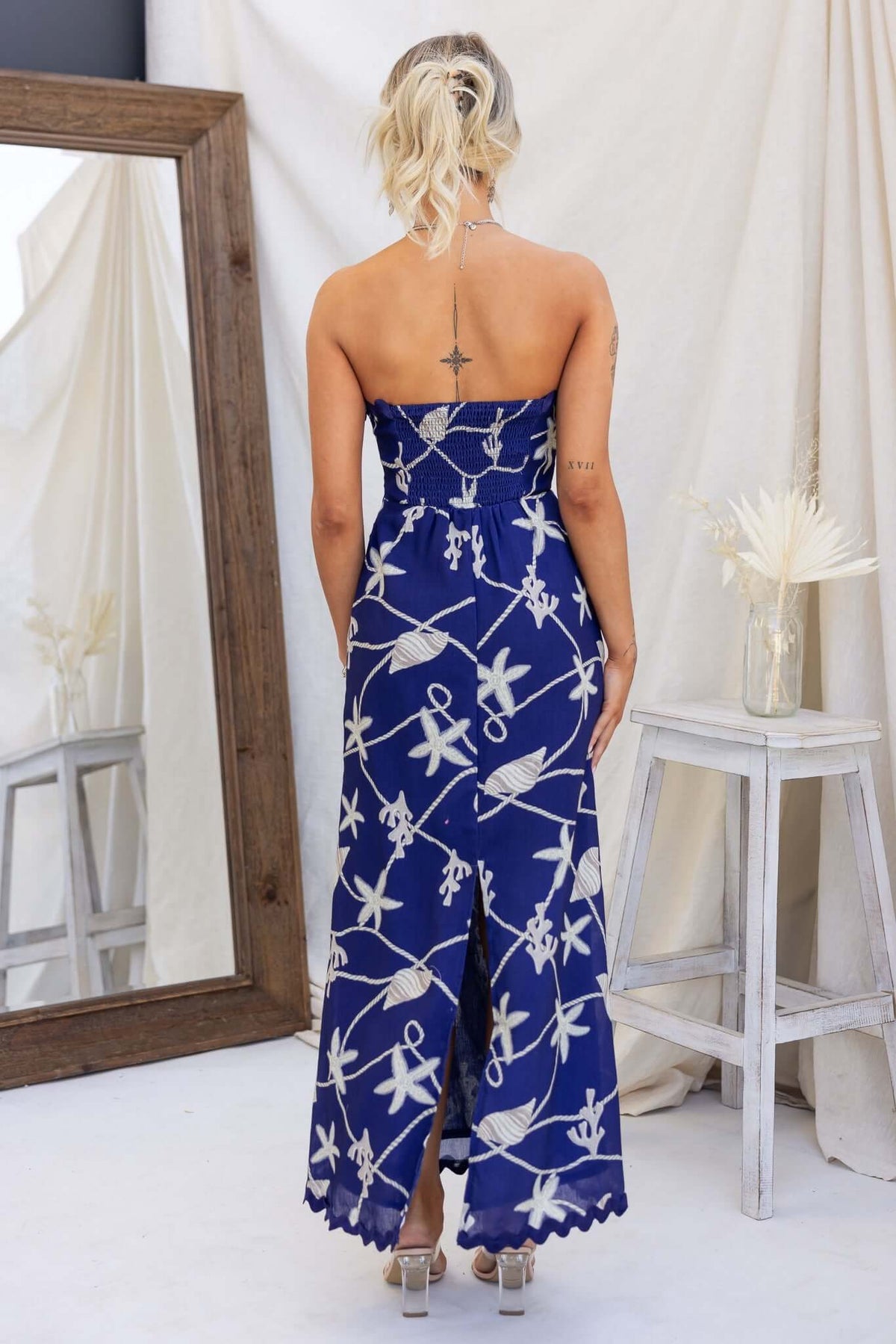 Back view of a navy strapless maxi dress with unique design and side split, showcasing a stylish look. Perfect for summer.
