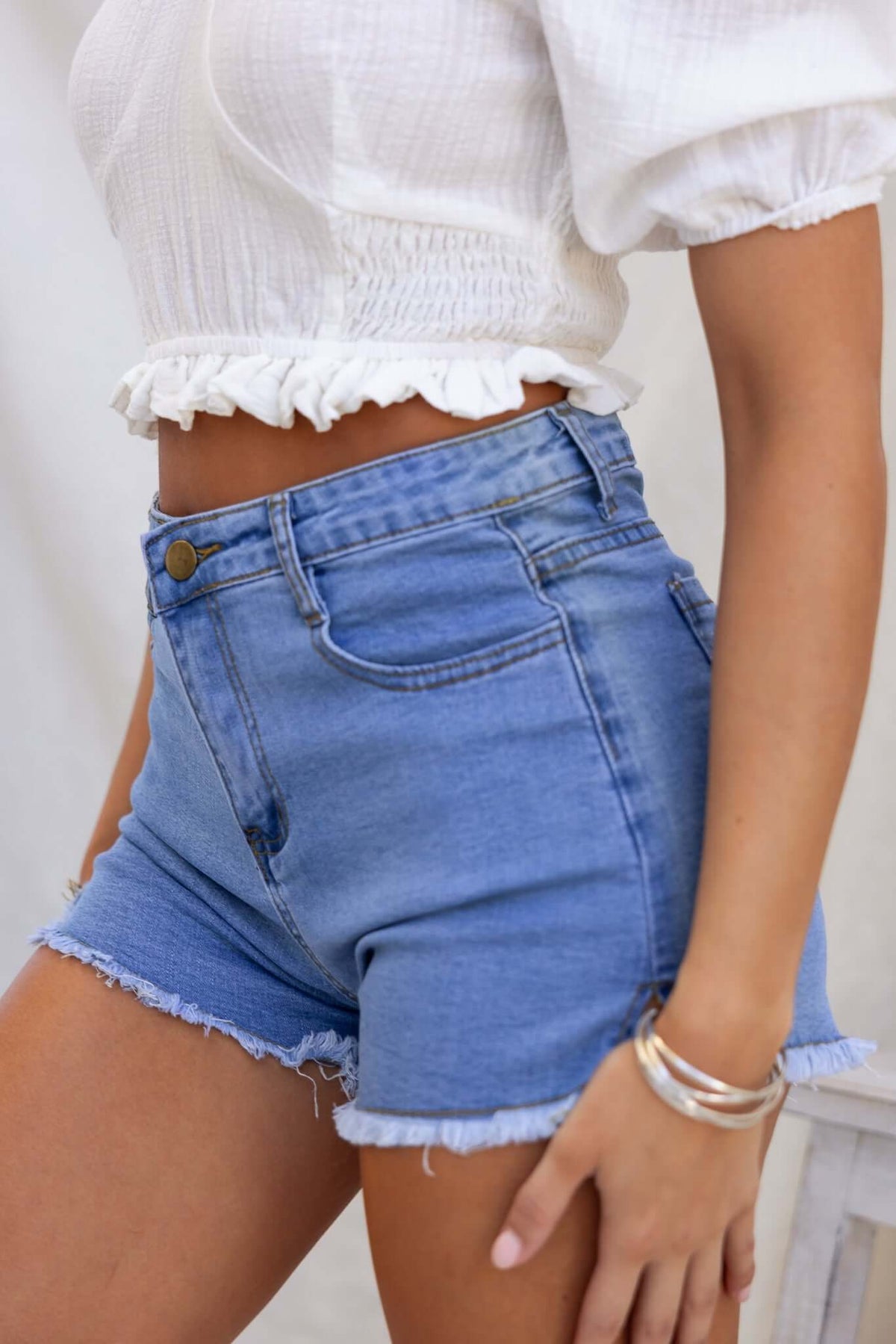 Model wearing Too Cool Denim Shorts featuring high-mid waist fit and frayed hemline.