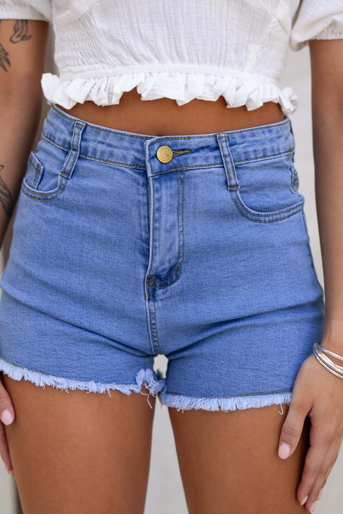 Too Cool Denim Shorts featuring high-mid waist fit, frayed hem, and pockets in a stylish blue wash.