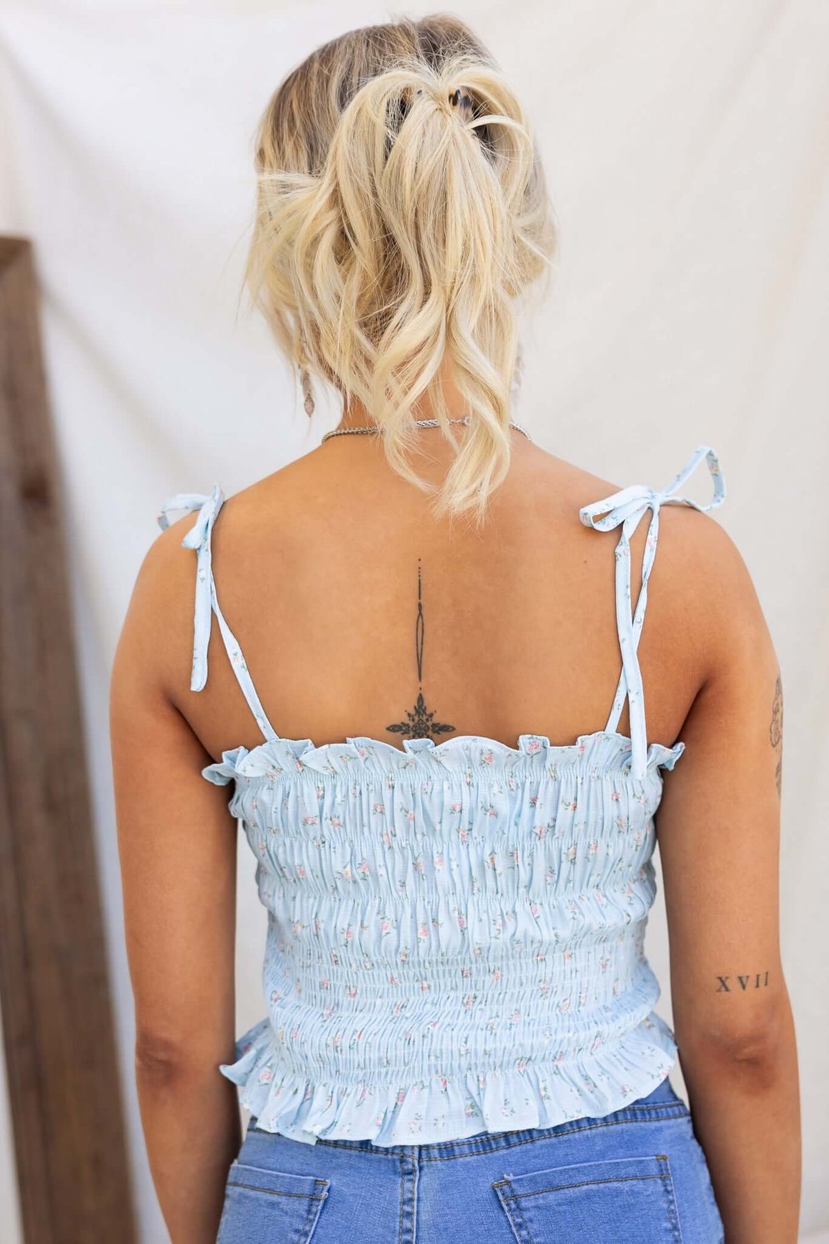 Iris Top in light blue with tie straps and elastic bodice, showing back design and ruffled hem.