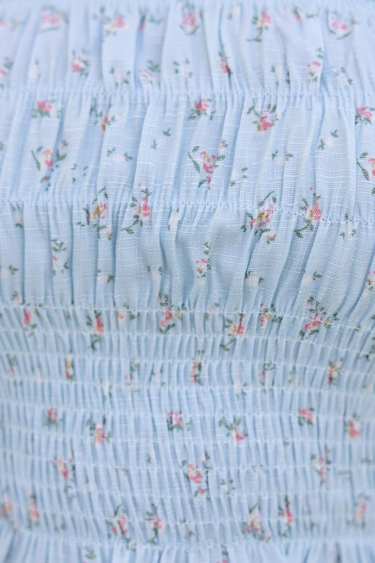 Close-up of light blue floral fabric with shirred detailing, showcasing the softness and texture of the Iris Top.