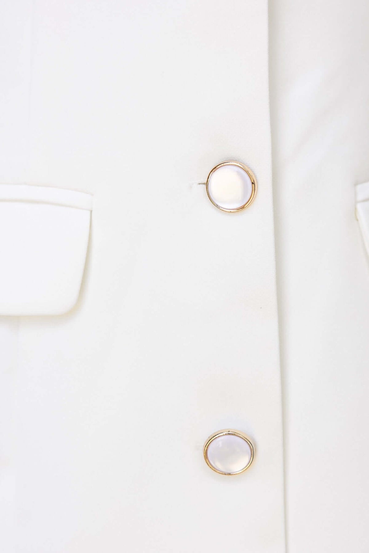 Close-up of white Hampton Dress featuring gold button details and faux pockets.
