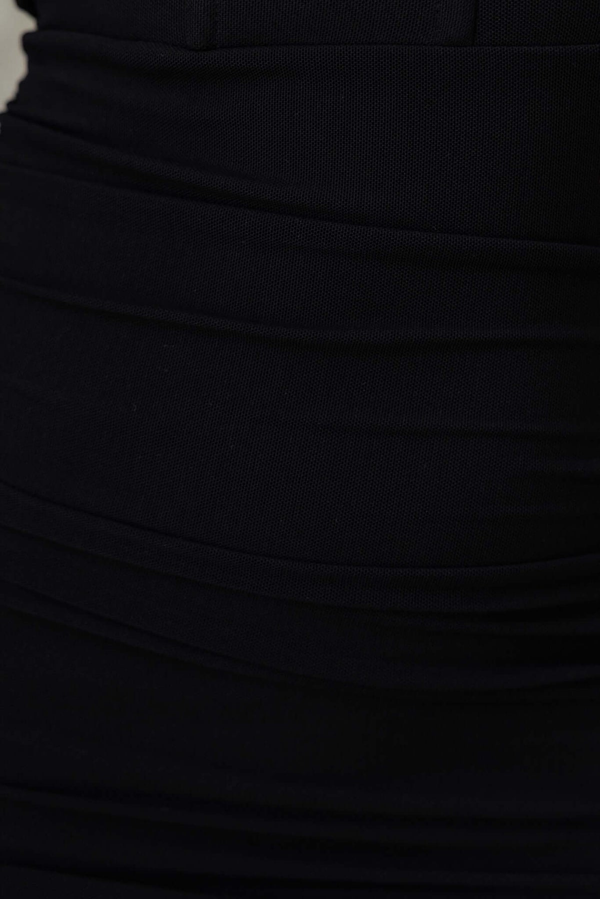 Close-up of black ruched fabric on Asha Midi Dress, showcasing stretch material and sleek design details.