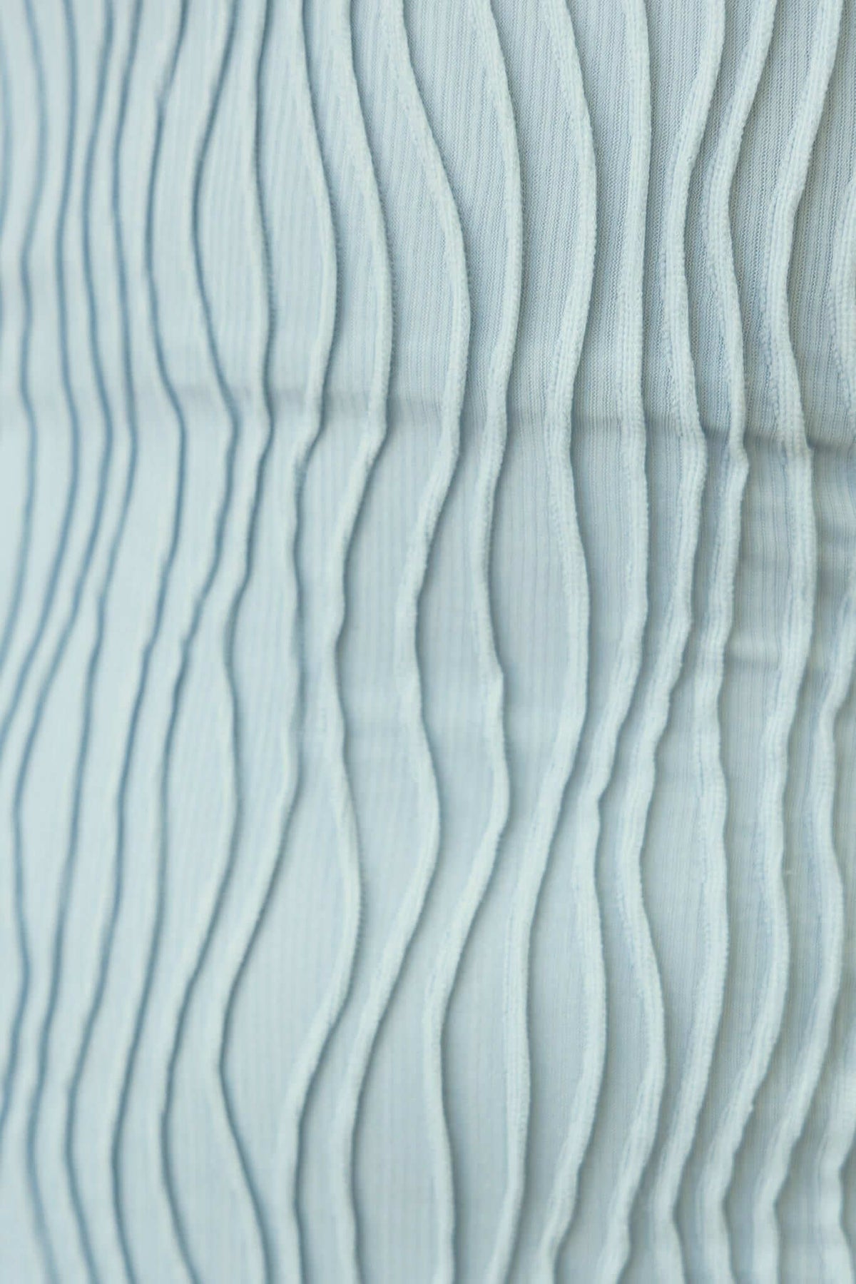 Close-up of textured fabric in light blue with wavy lines, ideal for a maxi dress design.