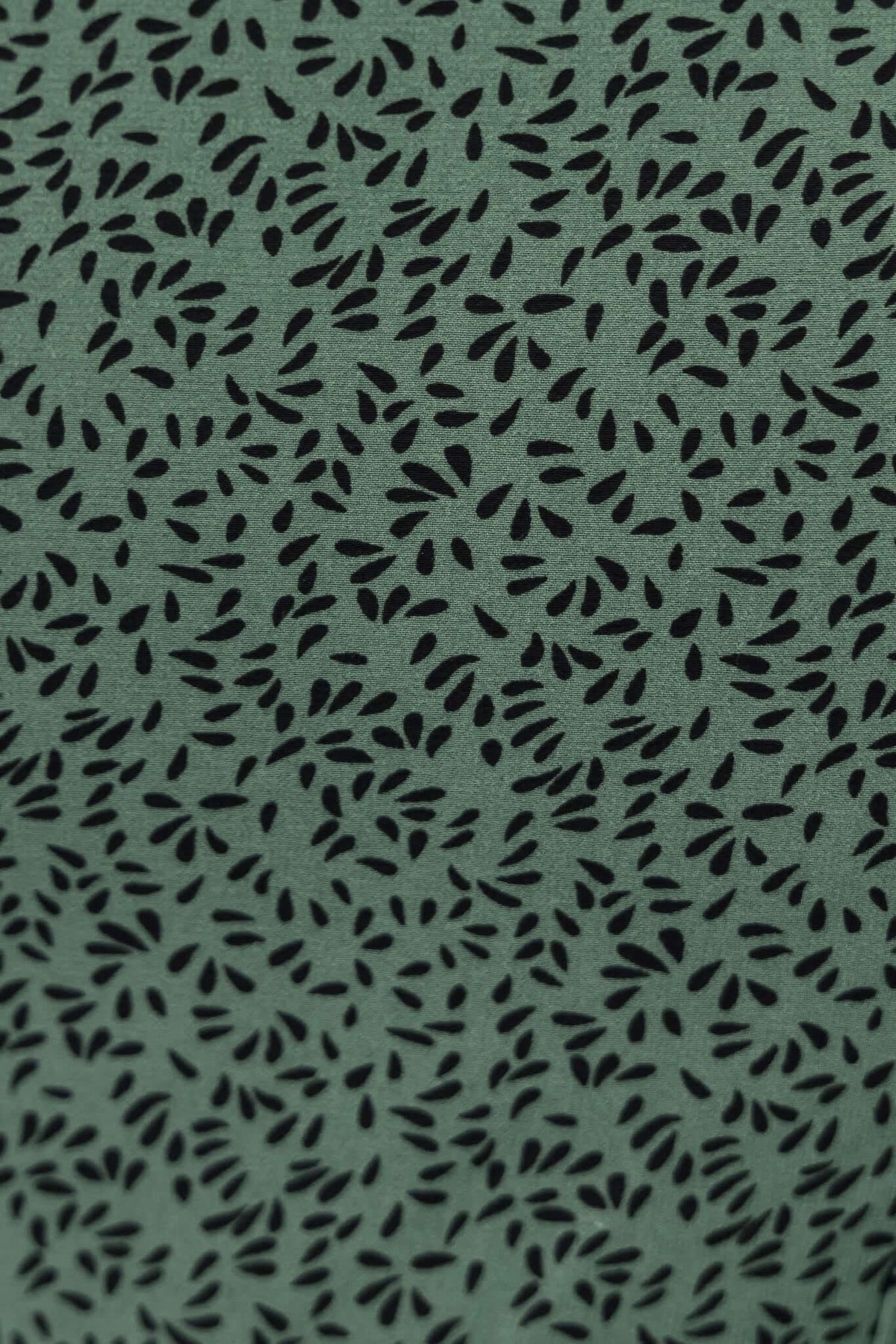 Close-up of green fabric with black leaf pattern, perfect for stylish and comfortable apparel.
