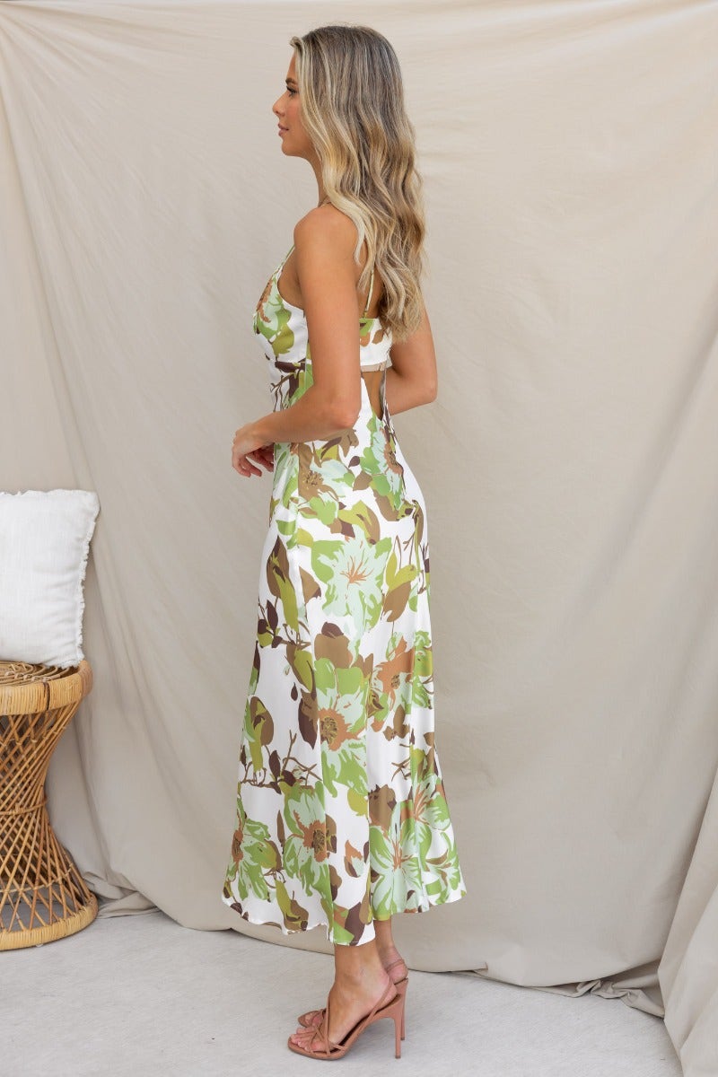 Brylee Maxi Dress in green and brown floral pattern, featuring adjustable straps and cut-out back, styled with sandals.