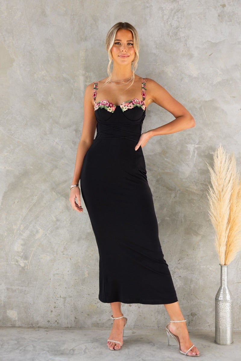 Black bodycon maxi dress with adjustable straps and floral embroidery, featuring a lace-up tie and lined stretch fabric.