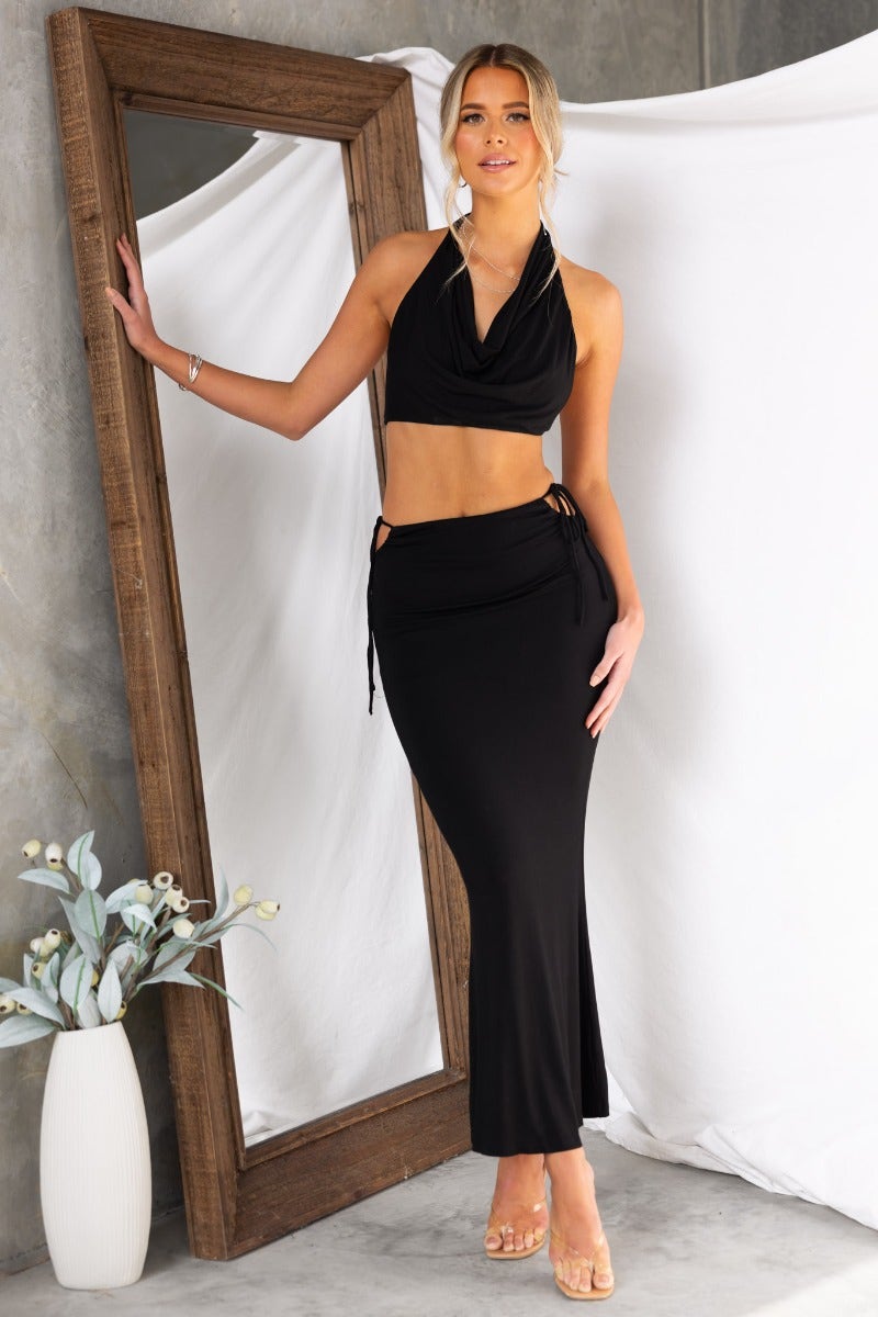 Model wearing a black Fearless maxi skirt with side tie detail and cut-out, showcasing a stylish casual outfit.