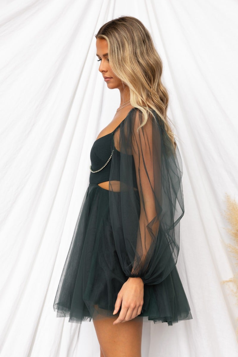 Side view of Fiona Dress, a dark green tulle dress with cut-out waist and elegant sheer sleeves.